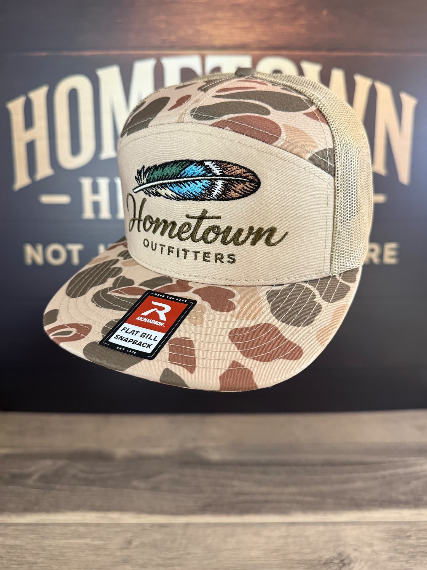 Duck camo trucker hat with embroidered Hometown Outfitters feather logo